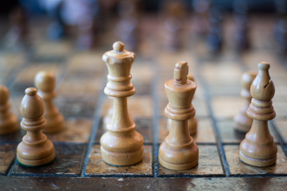 Wooden chess pieces on a worn board